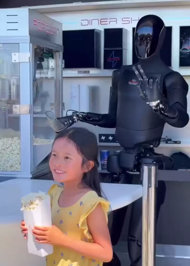 特斯拉 TeslaAI 官方微博发布首条视频:人形机器人卖爆米花,还可与顾客合影互动