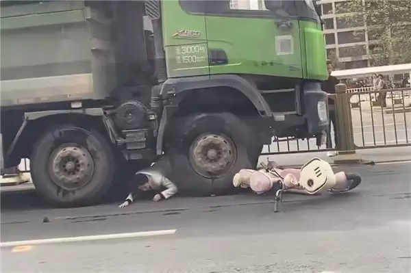 “死亡弯月”盲区太可怕！渣土车撞倒电动车 幸运女子从车底爬出