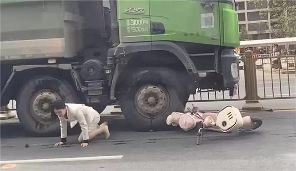 “死亡弯月”盲区太可怕！渣土车撞倒电动车 幸运女子从车底爬出
